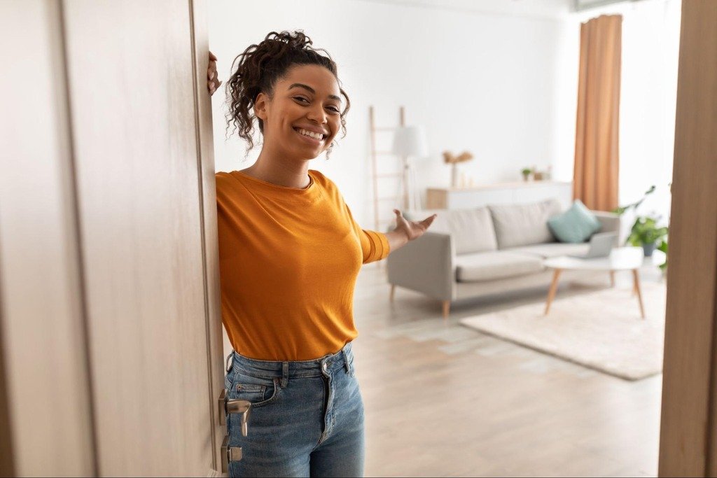 Alugar ou comprar imóvel? Entenda de uma vez por todas 6 mulher na entrada de apartamento depois de decidir entre alugar ou comprar imóvel