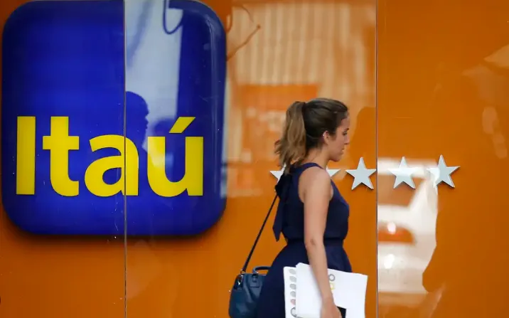 Banco Itaú anuncia vagas de trabalho em diversos setores. Mulher caminhando ao lado da logo do Banco Itaú, ilustrando novas oportunidades de emprego.