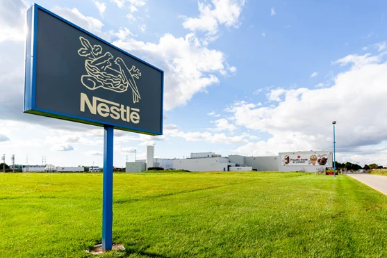 Nestlé anuncia novas oportunidades de trabalho no Brasil Fachada da fábrica da Nestlé com placa da empresa em destaque sob céu azul.