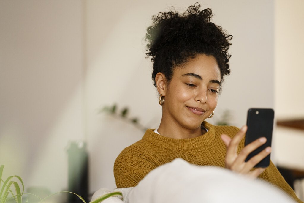 O que é negativado? Entenda o que significa e como limpar seu nome 2 mulher usando o celular para saber o que é negativado