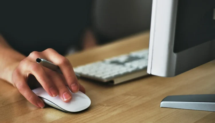 Trabalho aos domingos e feriados. Pessoa usando o mouse e o teclado, simbolizando a adaptação às novas regras de trabalho aos domingos e feriados.